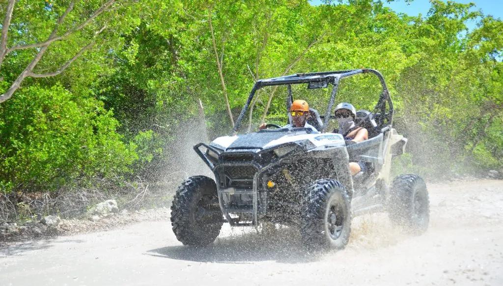 Personas conduciendo un buggy Polaris por un sendero tropical